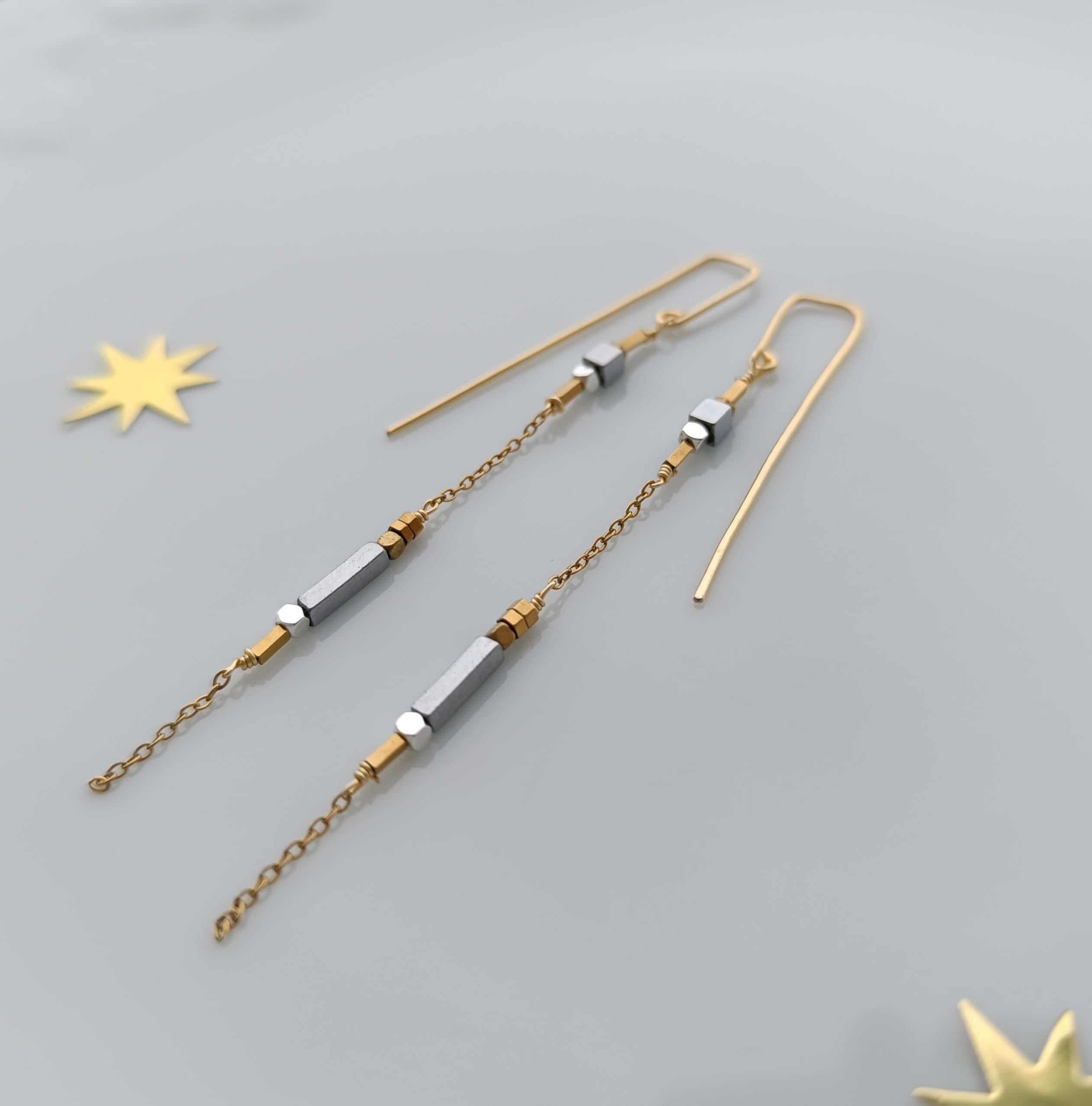 Minimalist long gold threader earrings with hematite beads, handcrafted with 18k gold-plated wire. Lightweight, modern jewelry on neutral background.