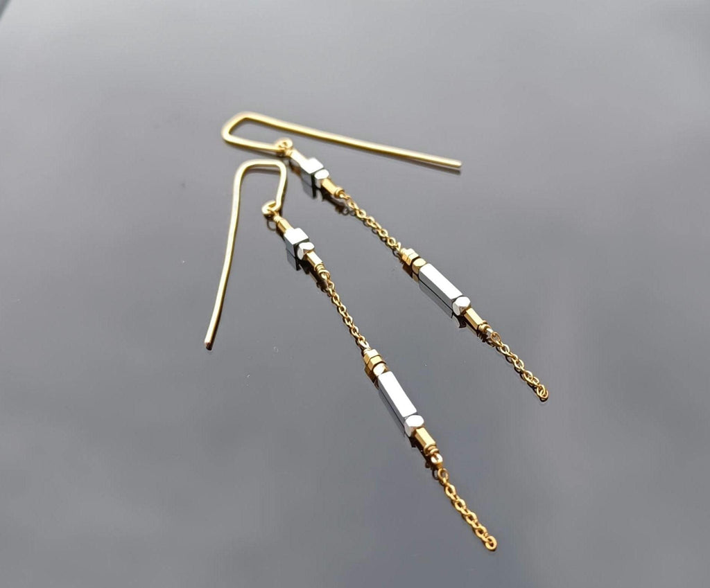 Minimalist long gold threader earrings with hematite beads, handcrafted with 18k gold-plated wire. Lightweight, modern jewelry on neutral background.
