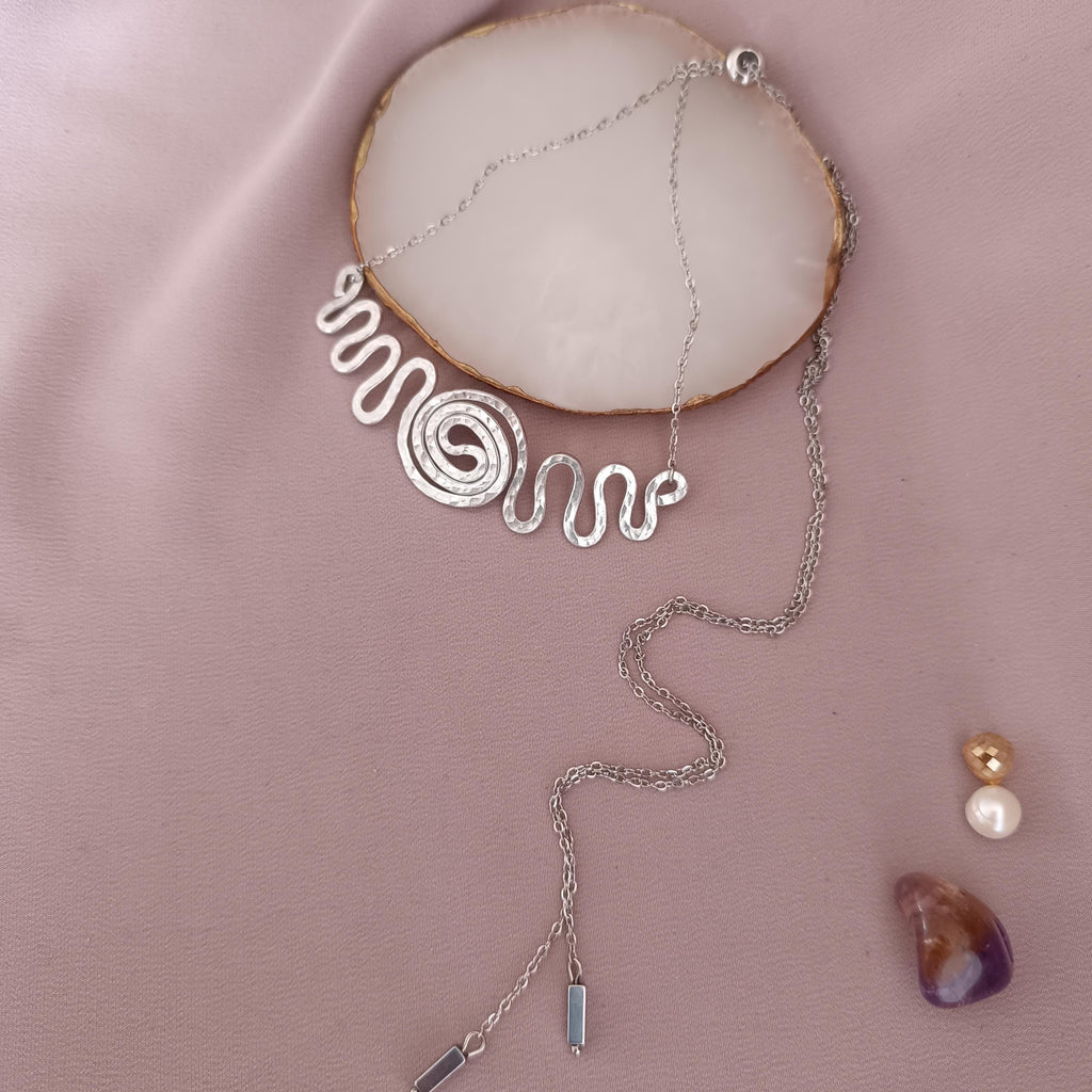 Detail shot of wire-wrapped spiral pendant with adjustable stainless steel chain and hematite beads.