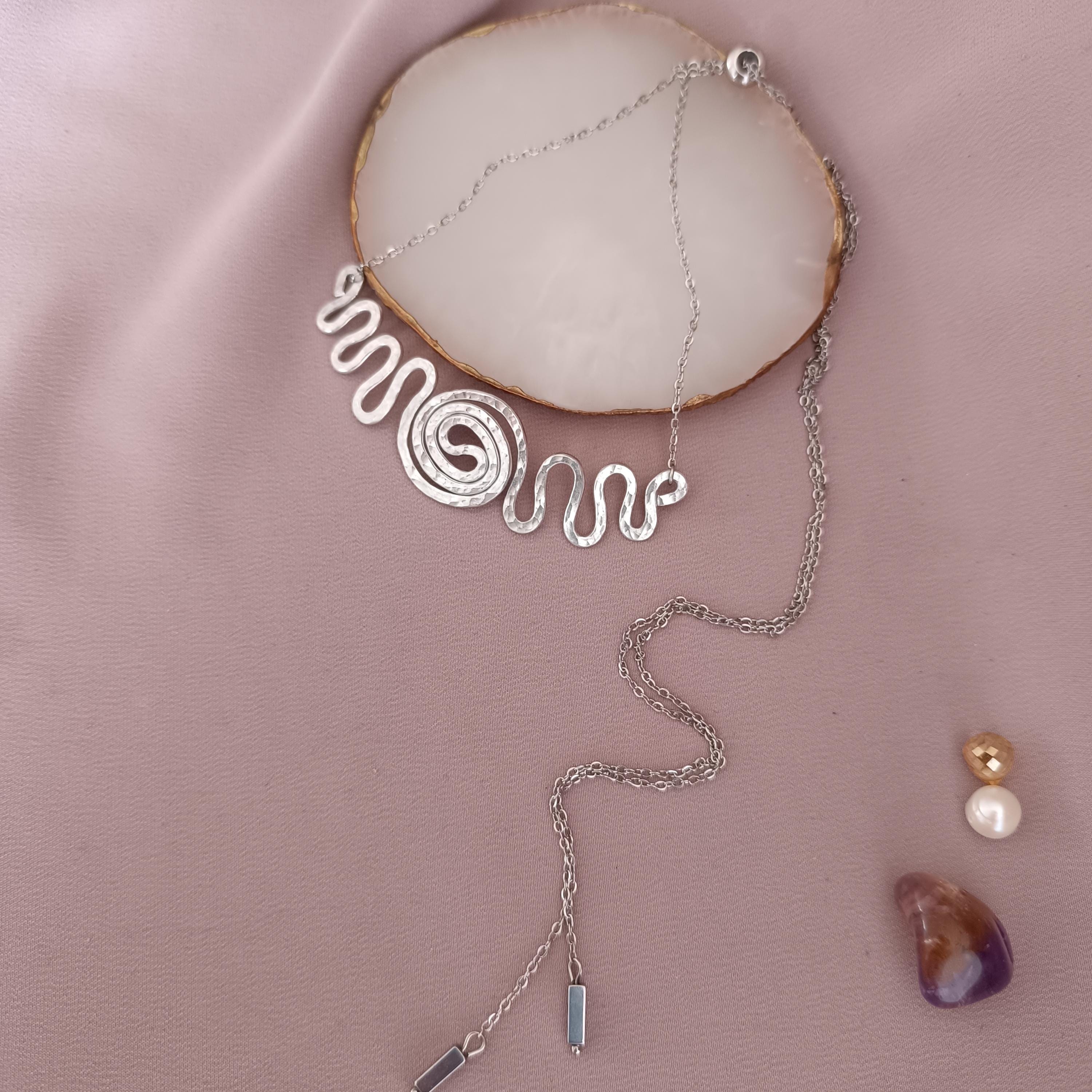 Detail shot of wire-wrapped spiral pendant with adjustable stainless steel chain and hematite beads.