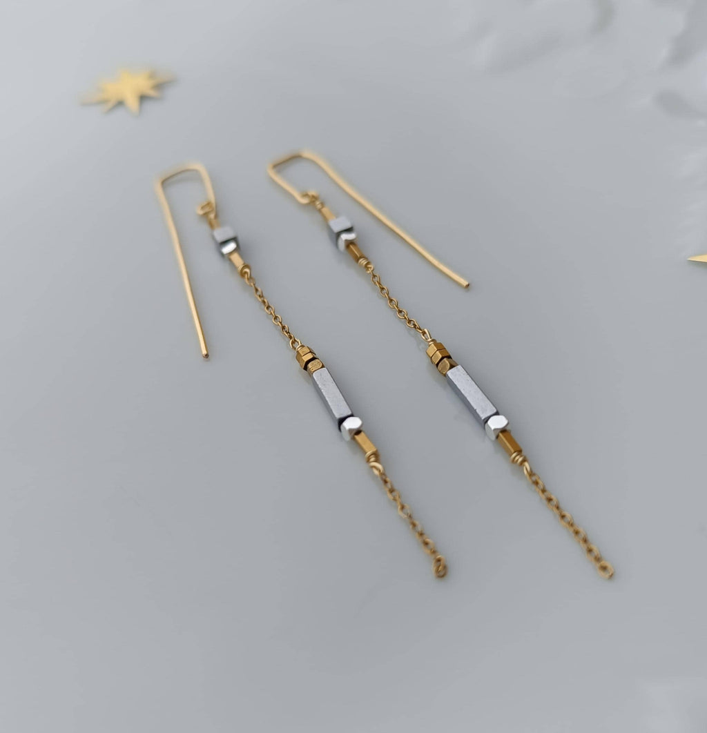 Minimalist long gold threader earrings with hematite beads, handcrafted with 18k gold-plated wire. Lightweight, modern jewelry on neutral background.