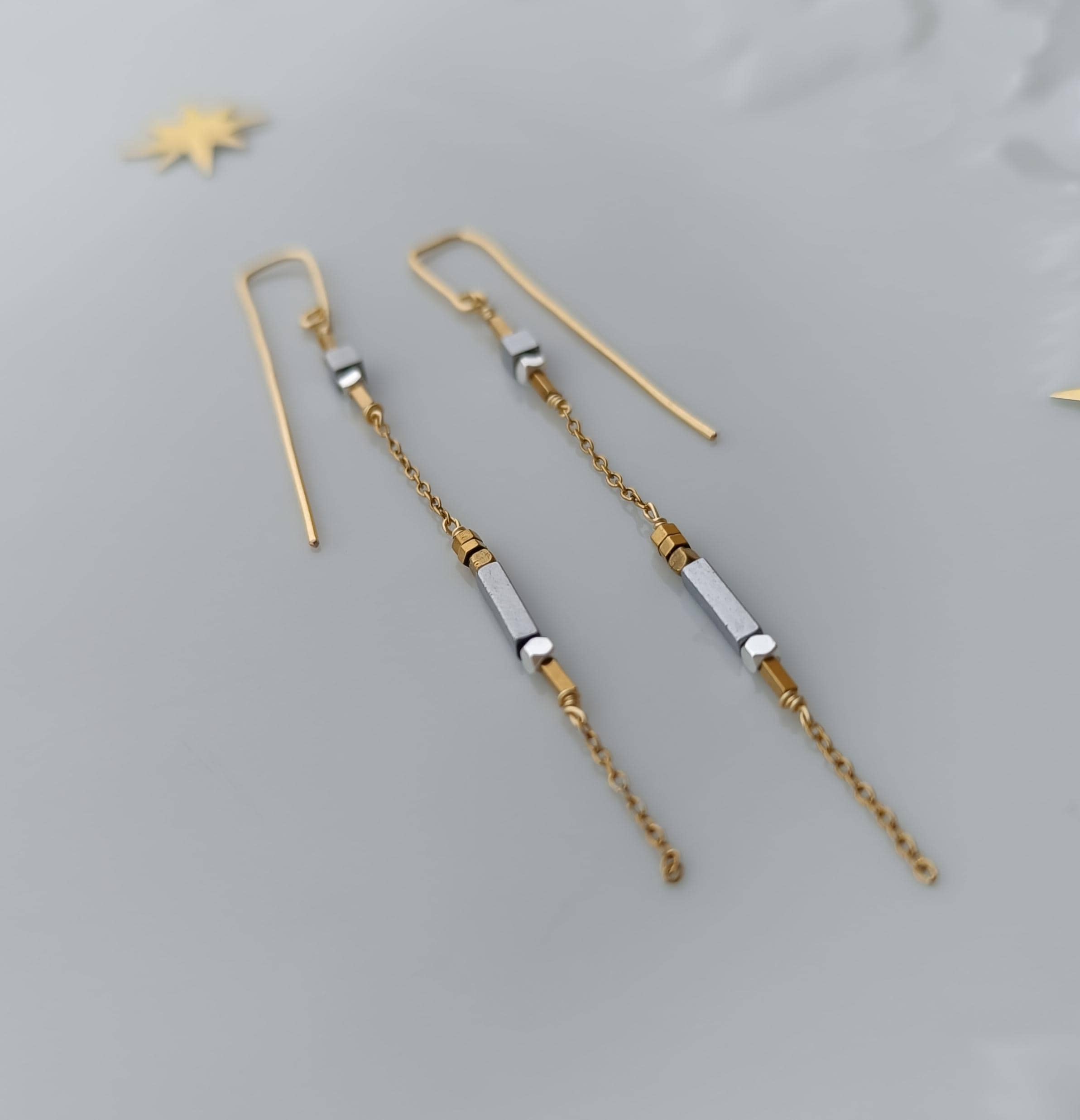 Minimalist long gold threader earrings with hematite beads, handcrafted with 18k gold-plated wire. Lightweight, modern jewelry on neutral background.