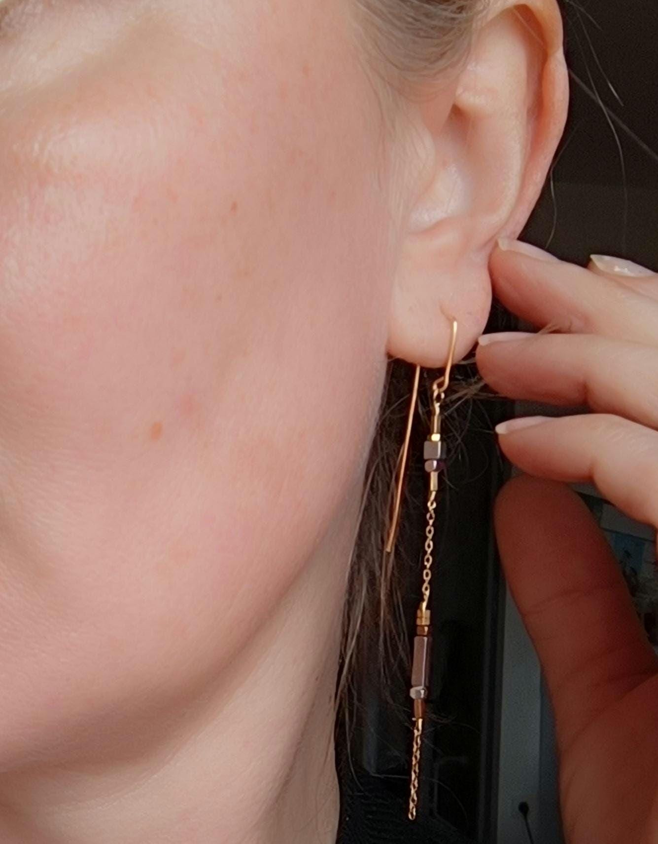 Minimalist long gold threader earrings with hematite beads, handcrafted with 18k gold-plated wire. Lightweight, modern jewelry on neutral background.