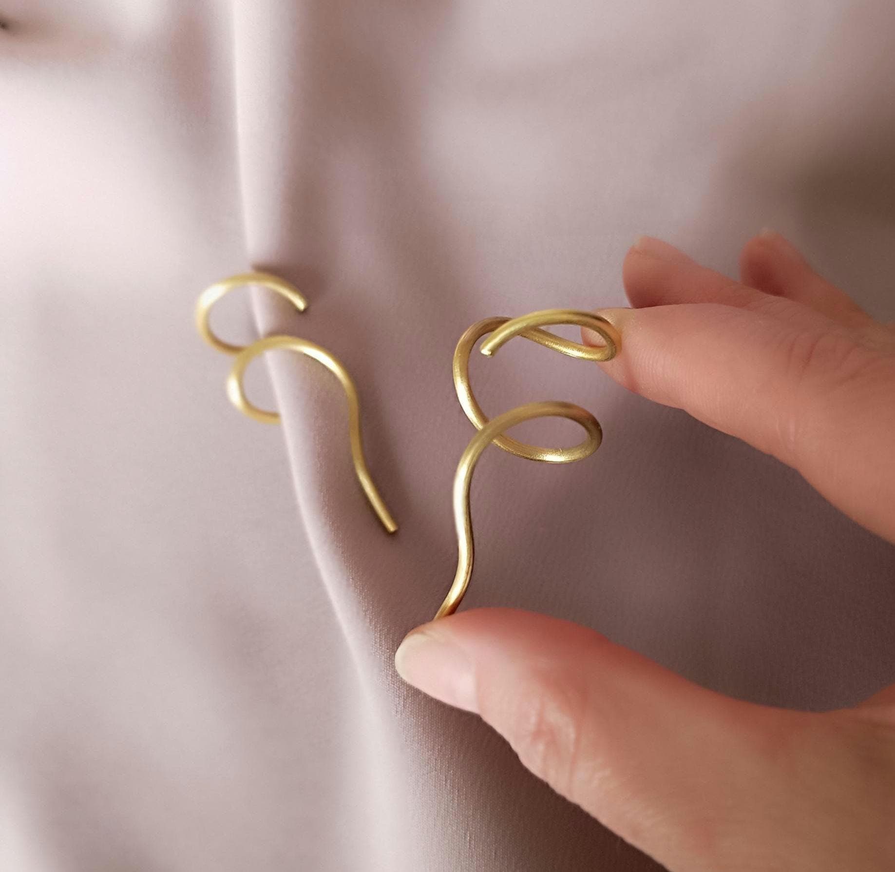 Minimalist brass ear cuff worn on ear – modern curved unisex jewelry piece in matte gold finish