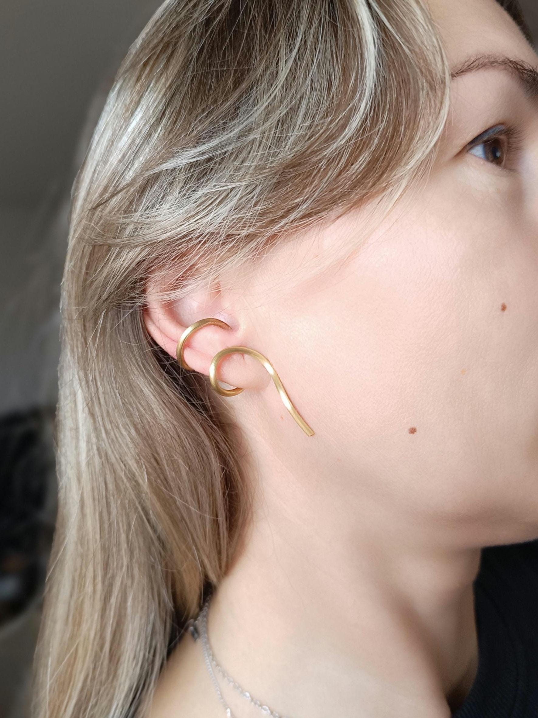 Minimalist brass ear cuff worn on ear – modern curved unisex jewelry piece in matte gold finish