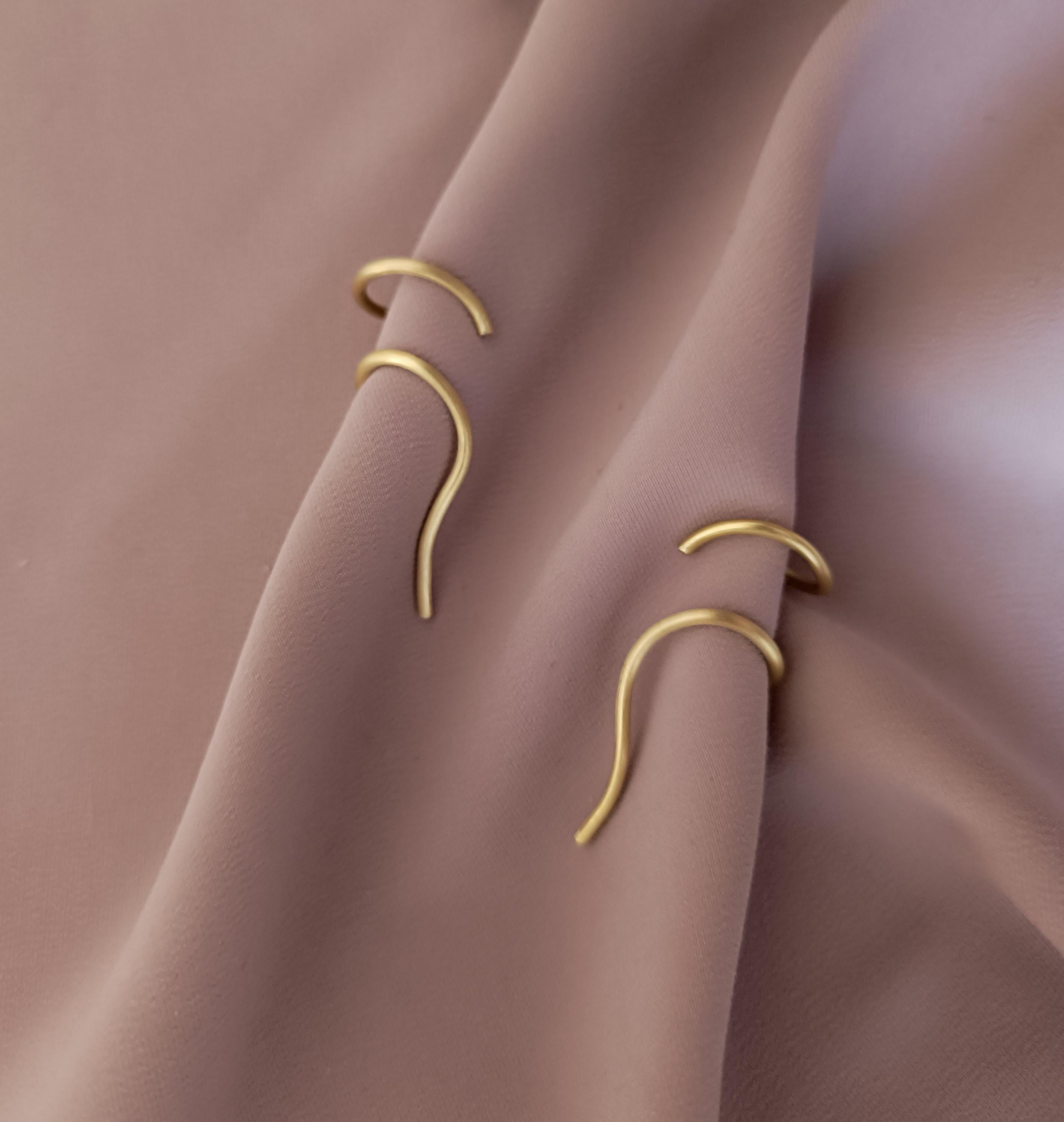 Minimalist brass ear cuff worn on ear – modern curved unisex jewelry piece in matte gold finish